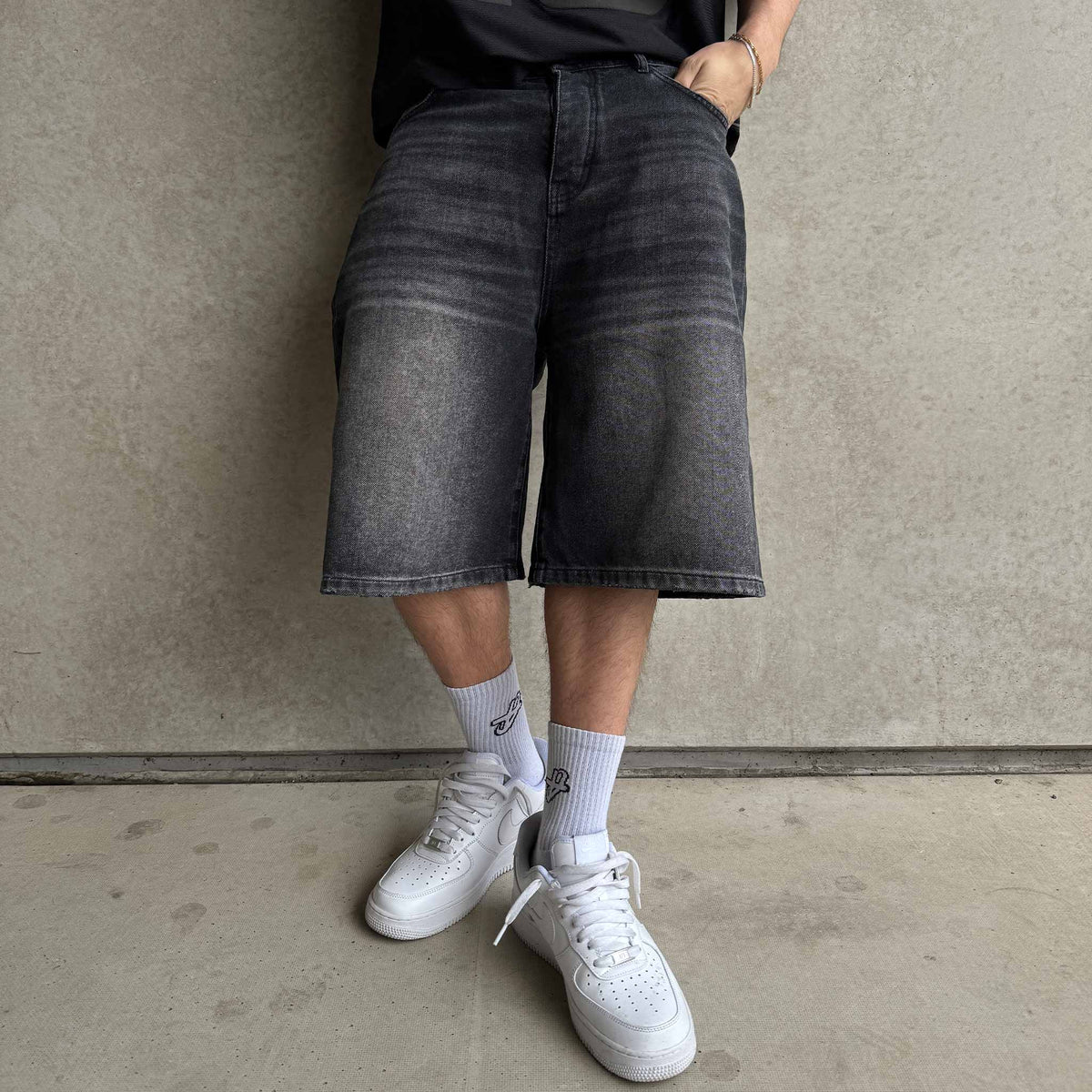 Star Denim Jorts Phantom Black on model, front view by a concrete wall