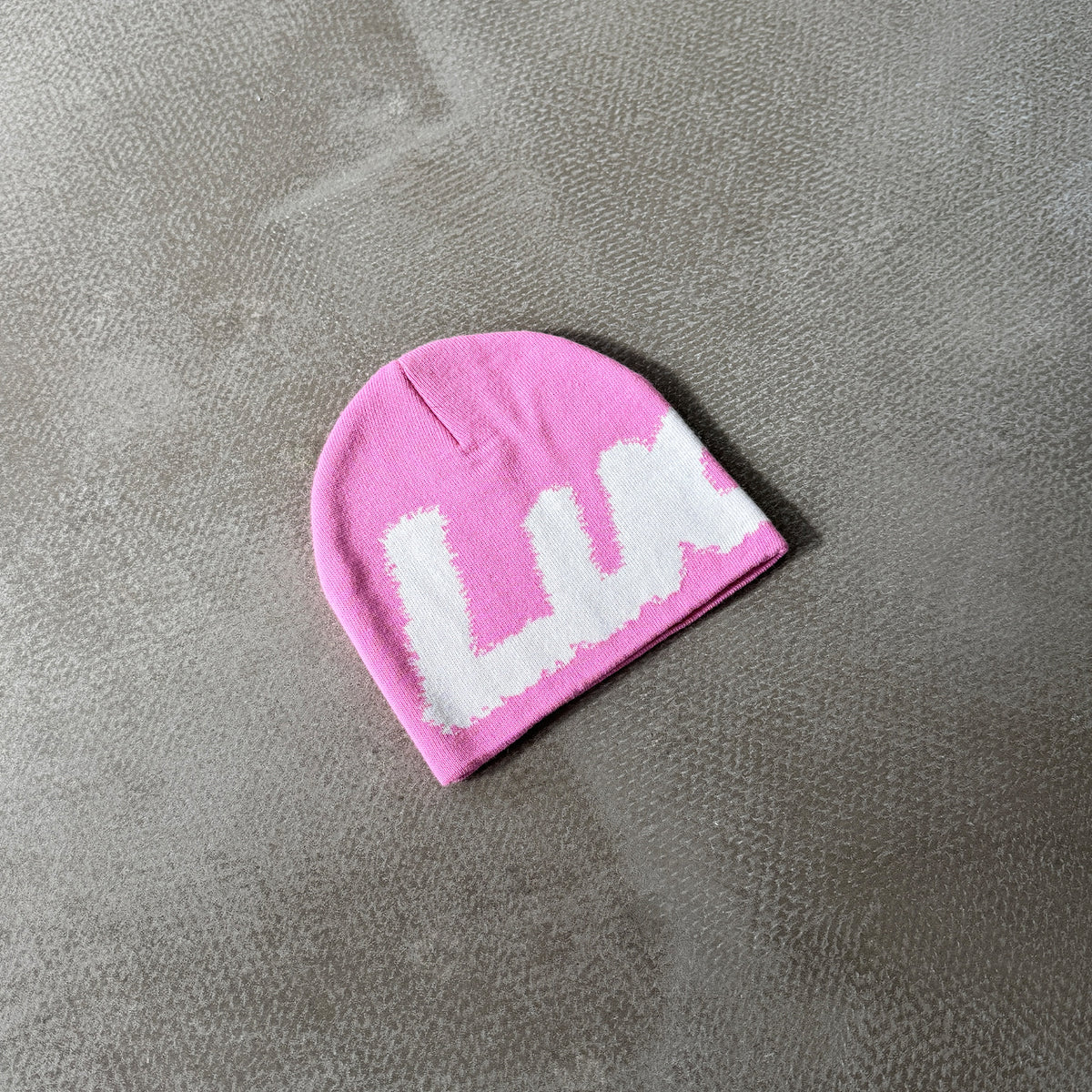 Lucid! Beanie Hyper Pink lying on concrete