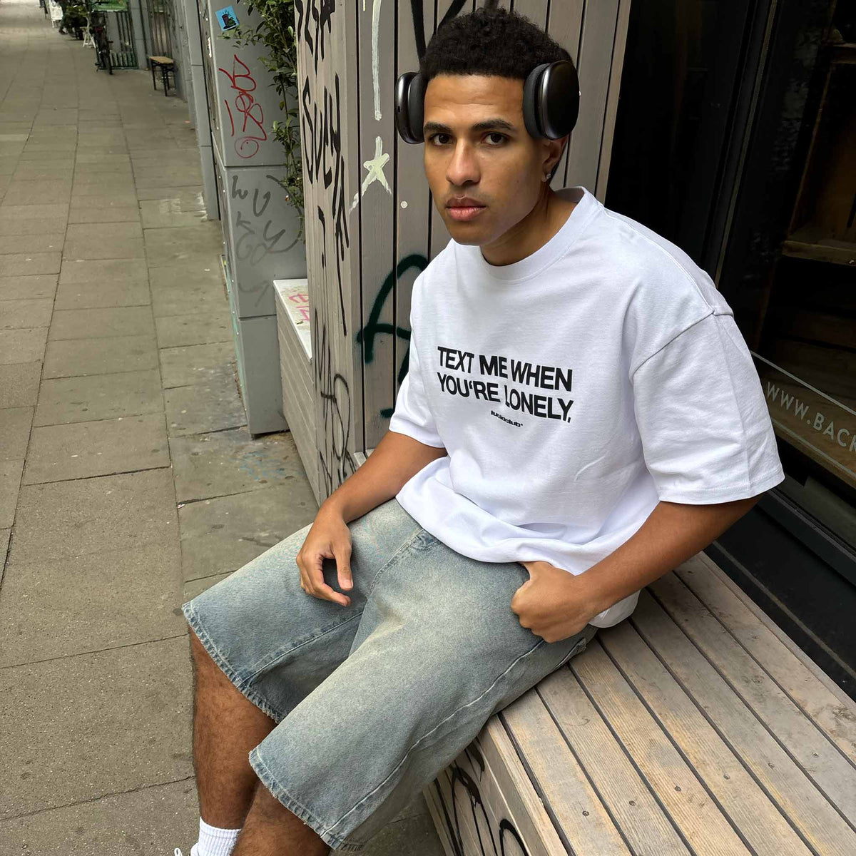Text Me T-Shirt White on model, sitting with jorts