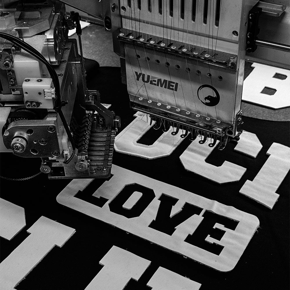 Stickmaschine stickt das Wort LOVE auf schwarzen Stoff