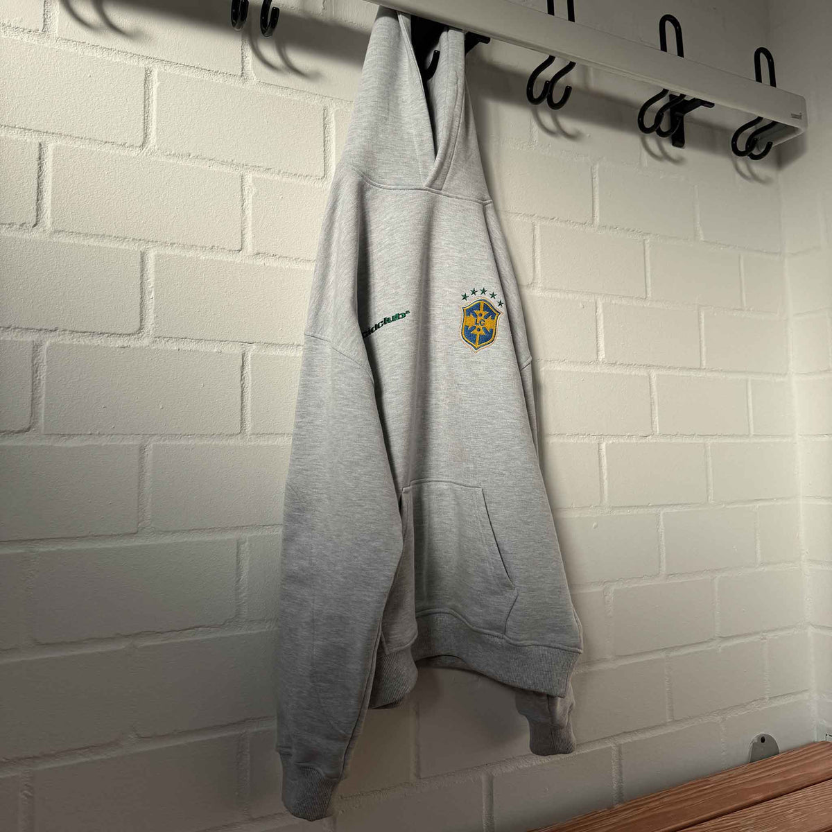 Brazil Hoodie Melange Grey hanging on a coat hook