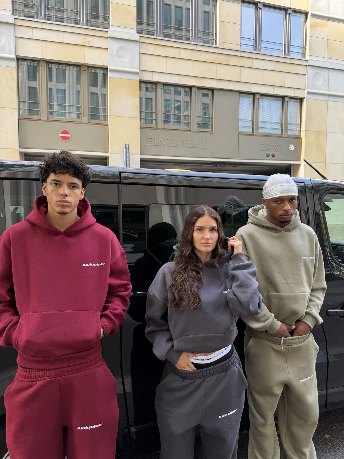 Drei Freunde in Cozy Tracksuits Wine Red, Dark Grey und Olive Green vor einem Van
